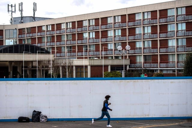 <p>Asylum seekers exit the a migrant hotel in London on February 24, 2021</p>