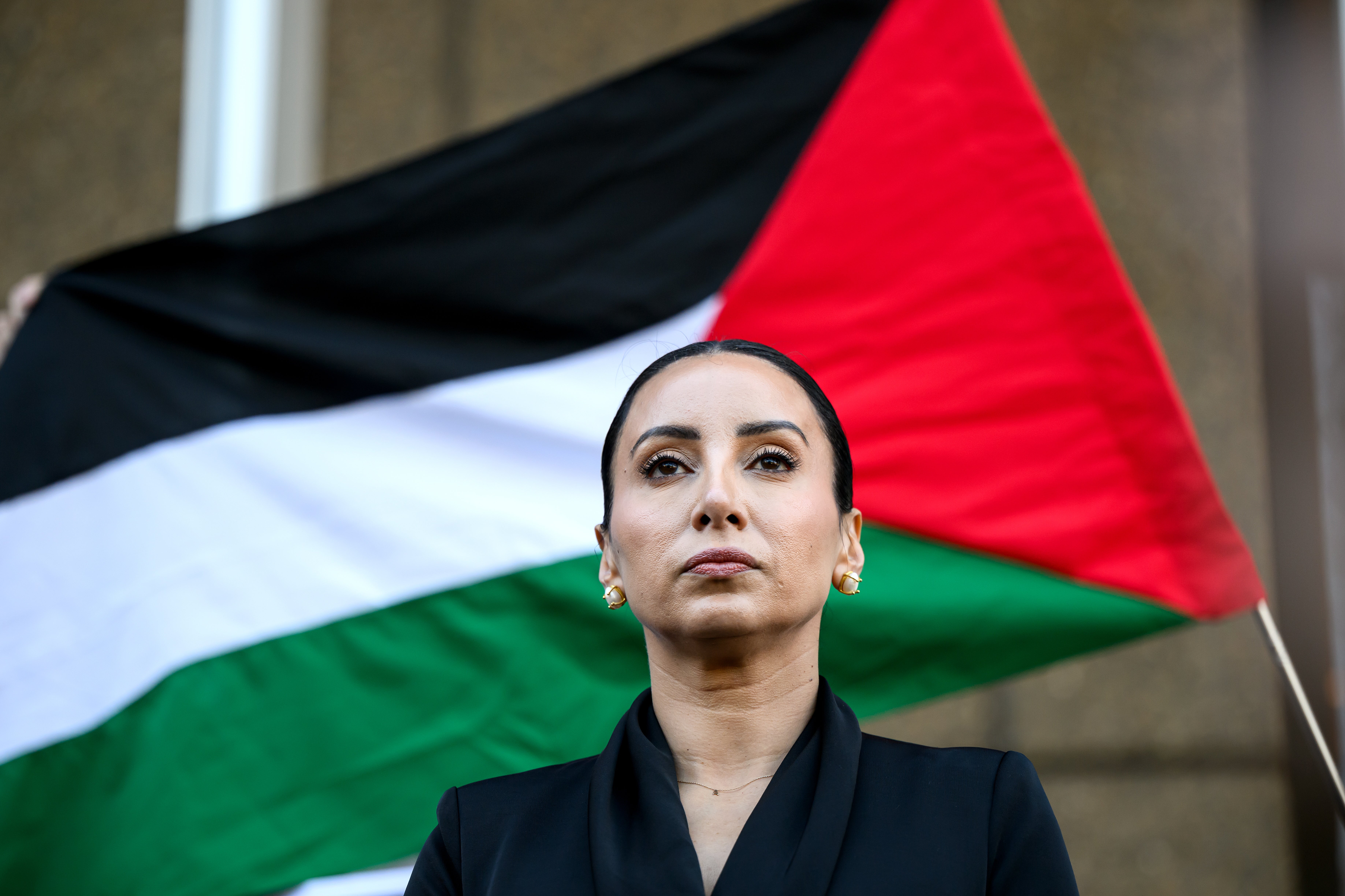 A Palestinian flag is displayed behind Antoinette Lattouf as she speaks to the media at the Federal Court of Australia in Sydney on 25 June 2025